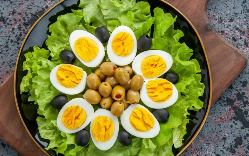 Salada com ovos cozidos, folhas de alface e azeitonas, destacando uma refeição balanceada.