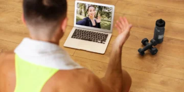 Homem treinando em casa com apoio de vídeo online, seguindo uma instrução para os exercícios .