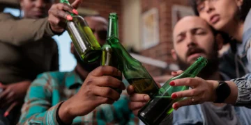 Grupo de amigos fazendo um brinde com garrafas de cerveja, celebrando em um evento social.