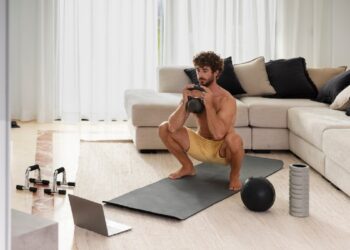 Homem realizando exercício de agachamento com peso em casa.