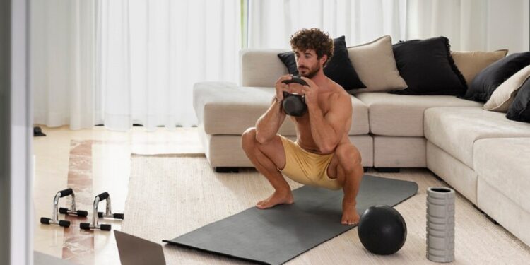 Homem realizando exercício de agachamento com peso em casa.