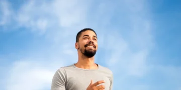 Homem sorridente praticando atividade ao ar livre, simbolizando bem-estar e felicidade.