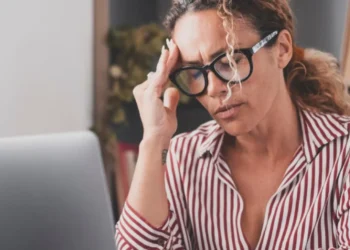 Mulher com dor de cabeça, símbolo de um possível sinal de falta de vitamina B12.