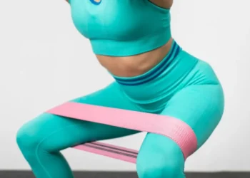 Mulher realizando agachamento com faixa elástica para treino de resistência.