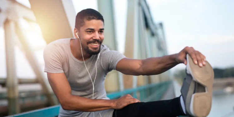 Homem jovem se alongando ao ar livre, representando os benefícios do treino físico para a memória.