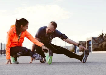 Homem e mulher alongando-se ao ar livre antes de uma atividade física."