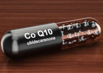 Cápsula de Coenzima Q10 sobre superfície de madeira, destacando seus benefícios para a saúde.