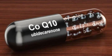Cápsula de Coenzima Q10 sobre superfície de madeira, destacando seus benefícios para a saúde.