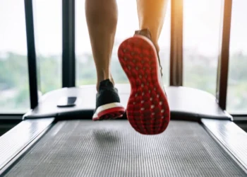 Close-up de tênis esportivo em movimento na esteira, destacando a corrida.