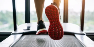 Close-up de tênis esportivo em movimento na esteira, destacando a corrida.