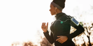 Mulher correndo ao ar livre com fones de ouvido, aproveitando os benefícios da caminhada para emagrecer.