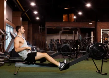 Homem realizando exercício de remada baixa em academia, focado no fortalecimento das costas.