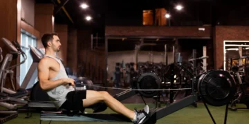 Homem realizando exercício de remada baixa em academia, focado no fortalecimento das costas.