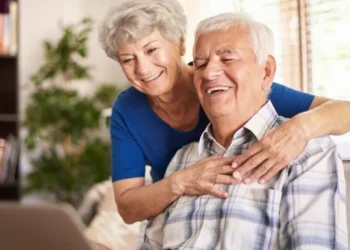 Casal de idosos sorrindo e utilizando um computador, refletindo a importância do cuidados preventivos para saúde na terceira idade.