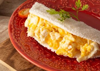 Tapioca recheada com ovos mexidos, servida em um prato vermelho