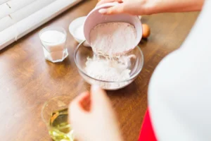 Pessoa preparando um ingrediente em pó, que pode ser utilizado para consumo de albumina em receitas como shakes ou misturado em alimentos.