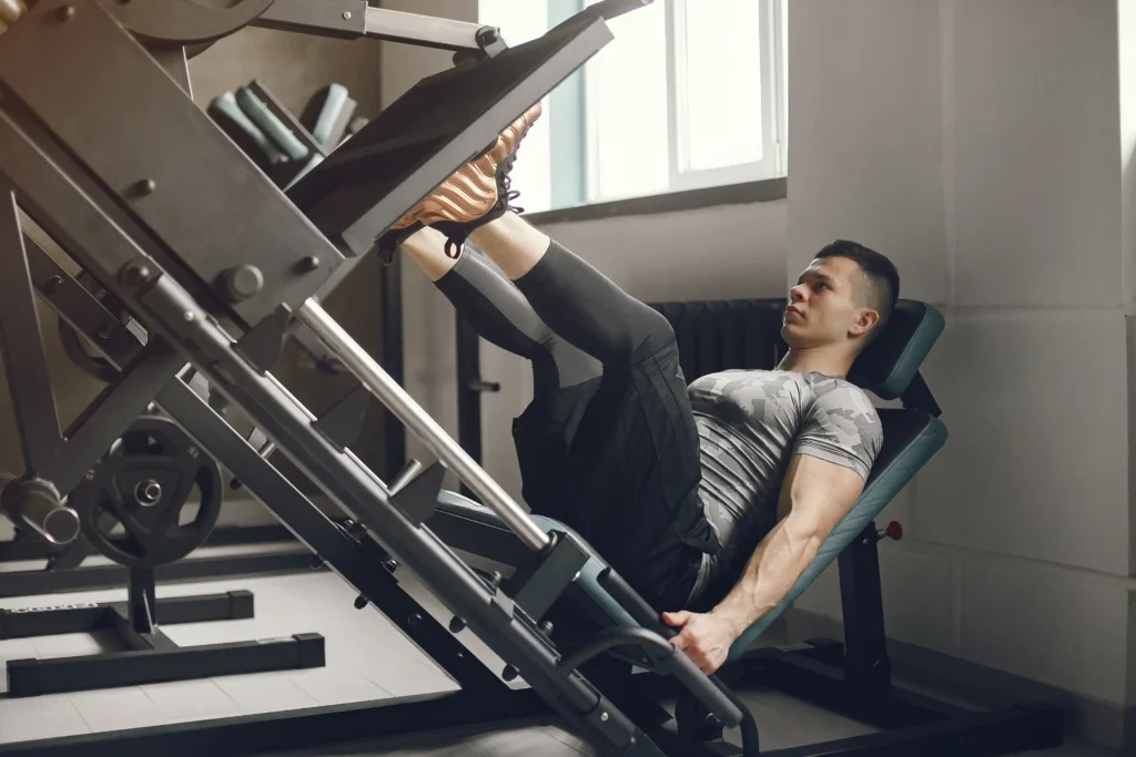 Homem fazendo exercício de leg press com foco nos quadríceps em uma academia moderna.