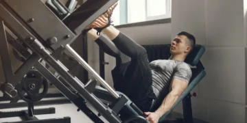 Homem fazendo exercício de leg press com foco nos quadríceps em uma academia moderna.