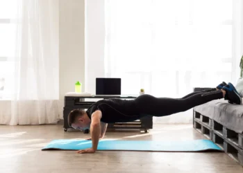 Homem fazendo flexões em uma academia em casa, com foco no treinamento de força.