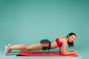 Mulher praticando exercícios físicos com um sorriso no rosto enquanto faz o exercício de prancha.