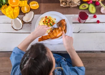 Mulher saboreando uma refeição saudável com alimentos frescos e orgânicos em uma mesa.