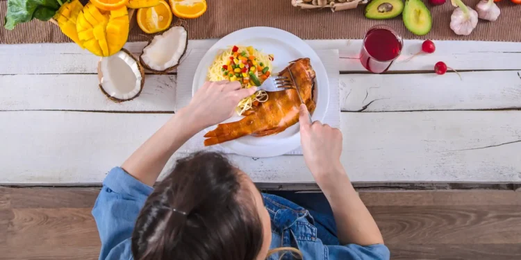 Mulher saboreando uma refeição saudável com alimentos frescos e orgânicos em uma mesa.