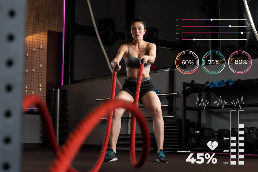 Mulher treinando com cordas de batalha em uma academia, monitorando seus dados de performance em tempo real.