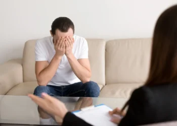 Homem visivelmente exausto e em crise emocional durante uma sessão de terapia com psicólogo.
