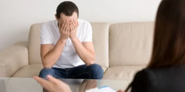 Homem visivelmente exausto e em crise emocional durante uma sessão de terapia com psicólogo.