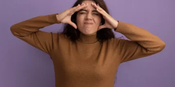 Mulher com expressão de frustração, com as mãos nas têmporas, demostrando ansiedade.