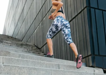 Mulher jovem subindo escadas como parte de um treino ao ar livre, focando em saúde e condicionamento físico.