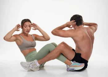 Mulher e homem praticando exercício juntos, fazendo abdominais no chão.