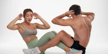 Mulher e homem praticando exercício juntos, fazendo abdominais no chão.