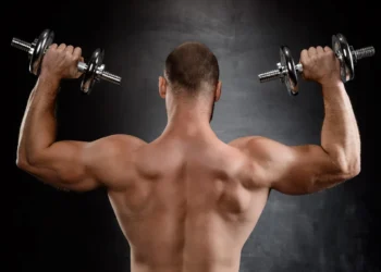 Homem forte levantando halteres, com foco no treino de força.