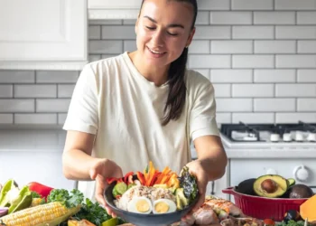 Mulher preparando uma refeição saudável com legumes e ovos, alimentos que ajudam a aumentar a vitamina D naturalmente.