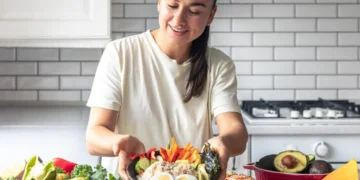 Mulher preparando uma refeição saudável com legumes e ovos, alimentos que ajudam a aumentar a vitamina D naturalmente.
