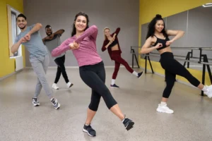 Pessoas praticando dança em grupo durante uma aula animada em estúdio.