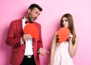 Homem e mulher segurando metades de coração partido, mostrando tristeza e arrependimento após término.