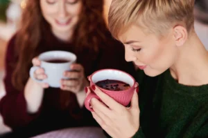 Mulher segurando uma xícara de chá quente, representando a escolha entre café e chá para o bem-estar.
