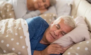 Casal idoso dormindo tranquilamente, transmitindo a importância de uma boa noite de sono para a saúde.