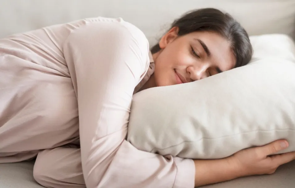 Mulher descansando de lado com expressão tranquila, simbolizando os benefícios do sono na posição lateral esquerda.