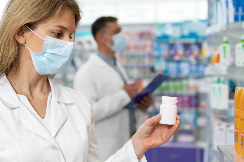 Dois farmacêuticos usando máscaras faciais analisam produtos em uma farmácia, simbolizando a fiscalização rigorosa da Anvisa em diversos pontos de venda.