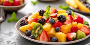 Salada colorida com frutas frescas como morango, kiwi, amora e abacaxi, ideal para uma alimentação leve e saudável.