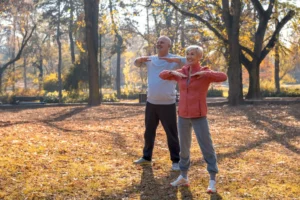 Casal de idosos praticando exercícios leves ao ar livre durante o outono