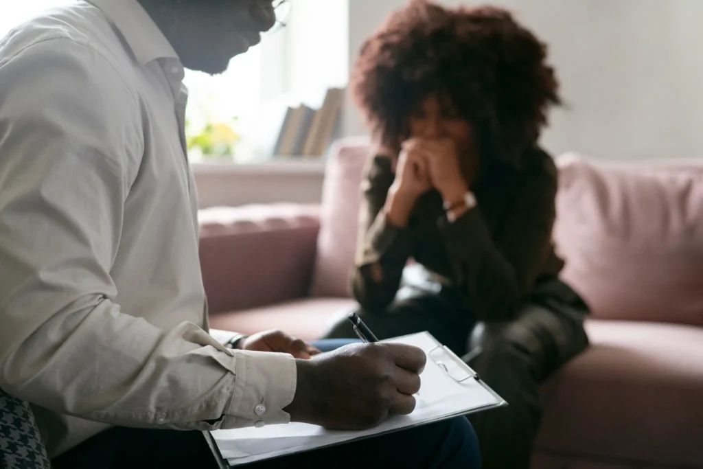 Pessoa em sessão de terapia, expressando emoções enquanto o terapeuta anota informações.