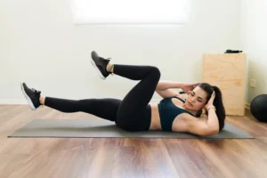 Mulher realizando exercício abdominal em bicicleta em ambiente doméstico, focada no treino.