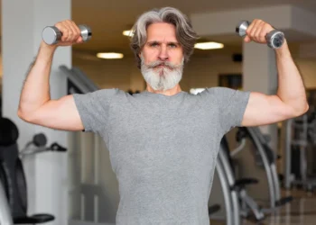 Idoso fazendo musculação com halteres para manter a saúde cerebral e física.