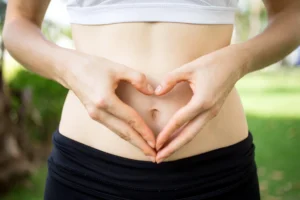 Pessoa fazendo um coração com as mãos sobre a barriga, representando saúde intestinal.