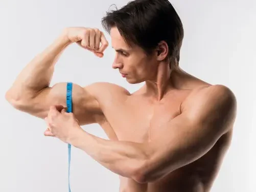 Homem medindo o braço para avaliar o aumento de massa muscular.