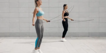 Duas mulheres praticando exercício de pular corda ao ar livre, destacando benefícios para o condicionamento físico.